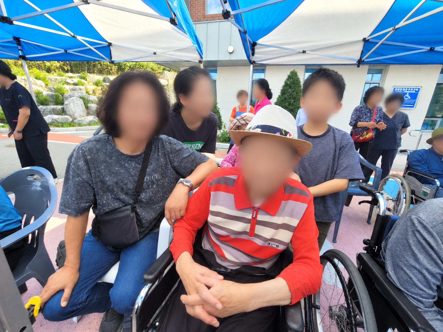 푸른 천막 아래 휠체어 가족 모임.png